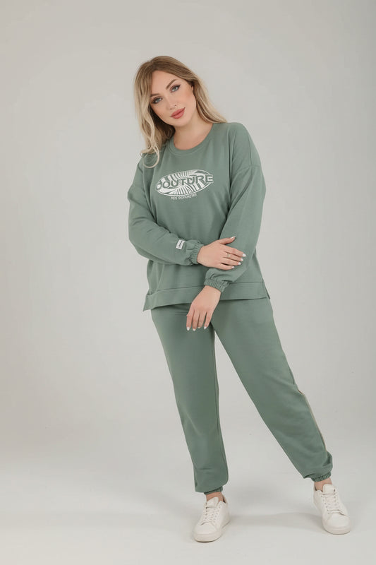 Woman wearing a green outfit with 'EL Sabah Homewear' branding, standing on a wooden bench.