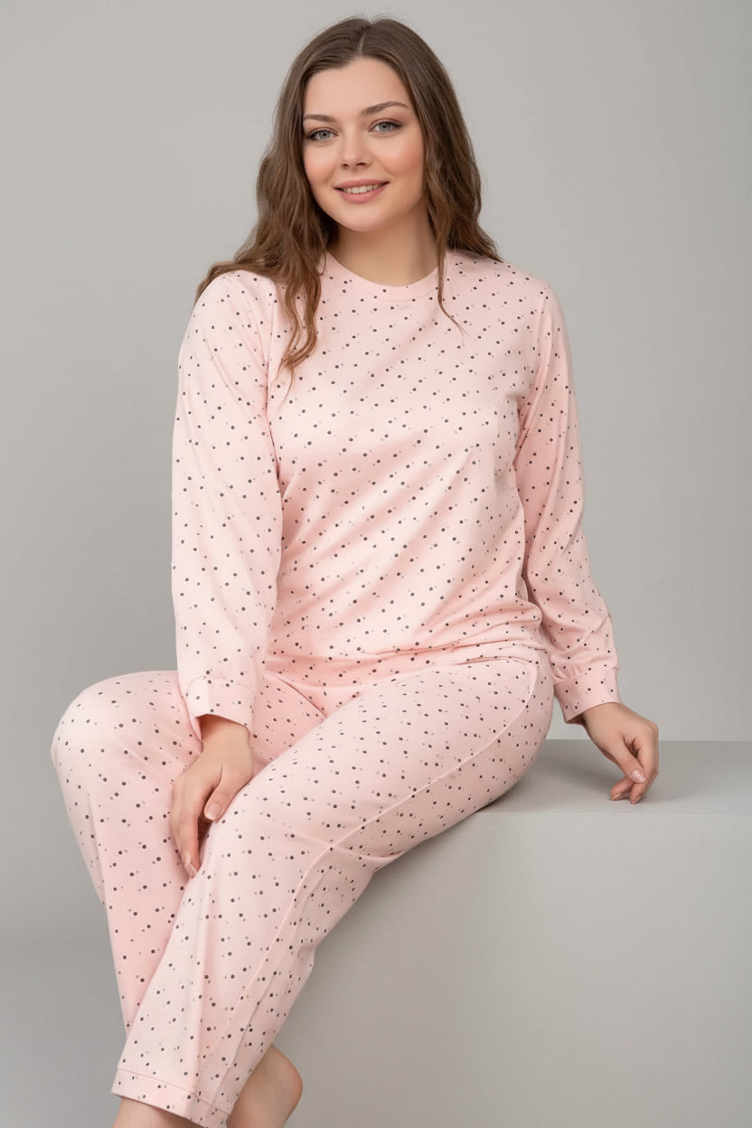 Woman wearing a pink polka dot pajama set sitting on a chair.